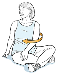 Mujer embarazada sentada con las piernas cruzadas, girando el torso hacia un lado.
