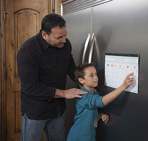 Man watching boy put sticker on calendar page.