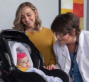 Healthcare provider and woman looking at baby in carrier.